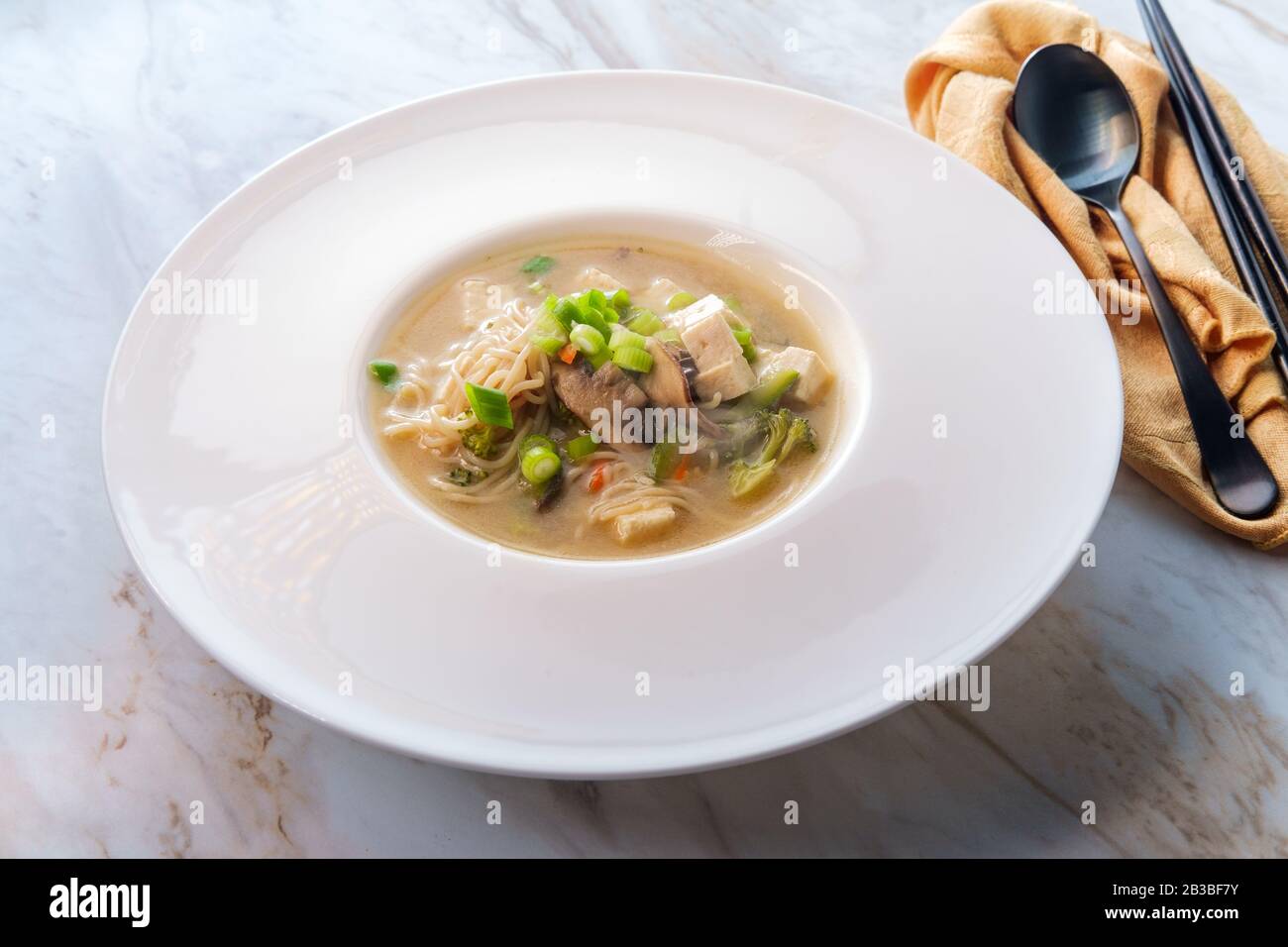 Bowl of loaded Japanese miso soup with noodles tofu julienned carrots and zucchini Stock Photo