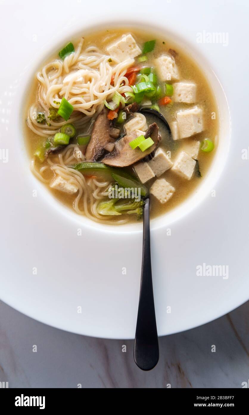 Bowl of loaded Japanese miso soup with noodles tofu julienned carrots and zucchini Stock Photo
