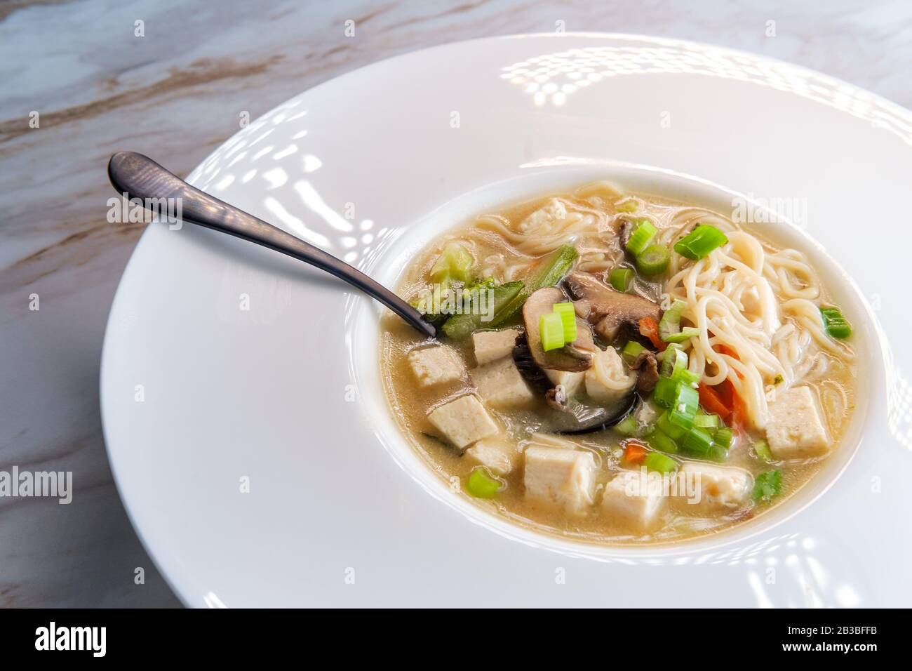 Bowl of loaded Japanese miso soup with noodles tofu julienned carrots and zucchini Stock Photo