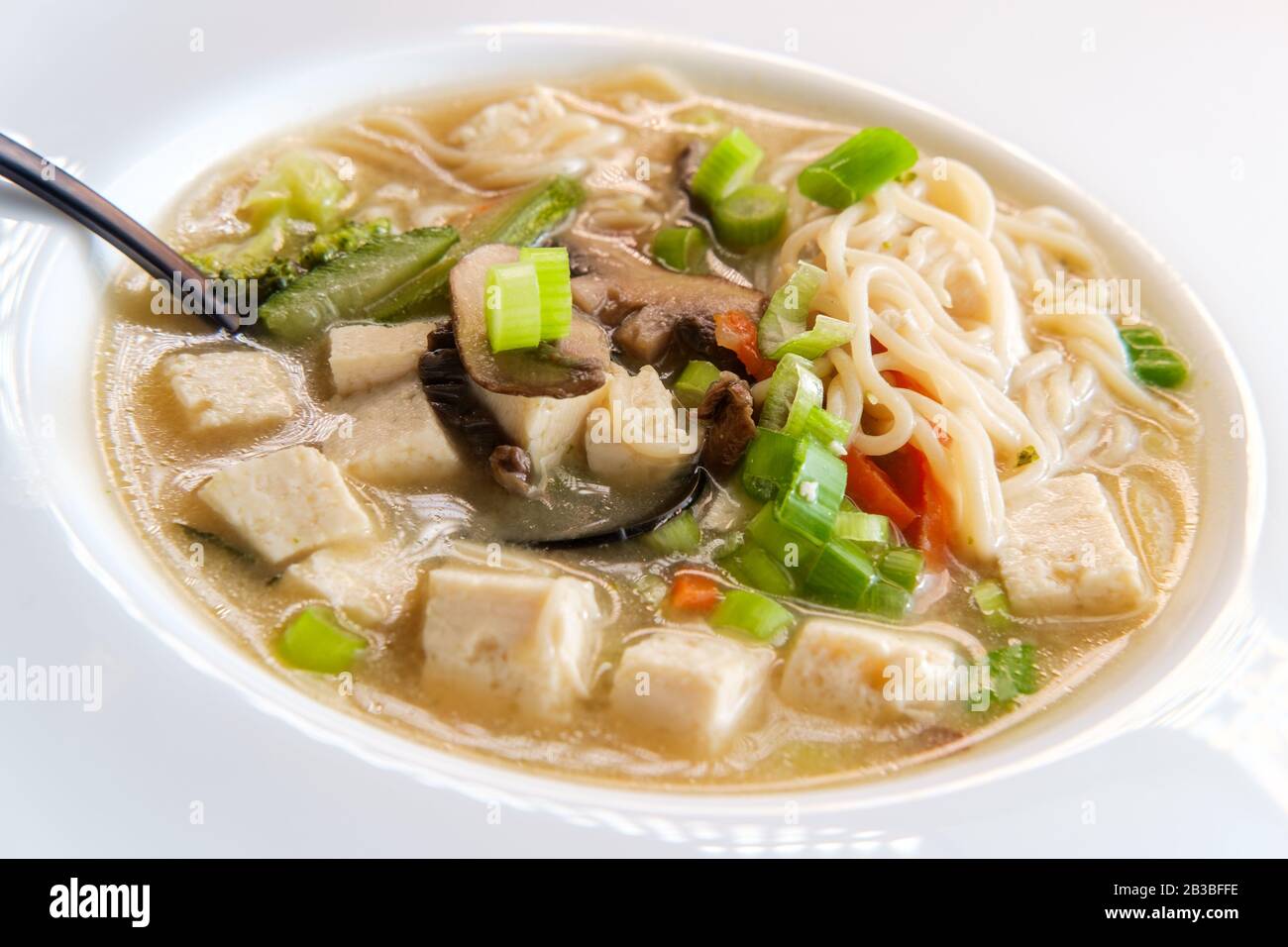 Bowl of loaded Japanese miso soup with noodles tofu julienned carrots and zucchini Stock Photo