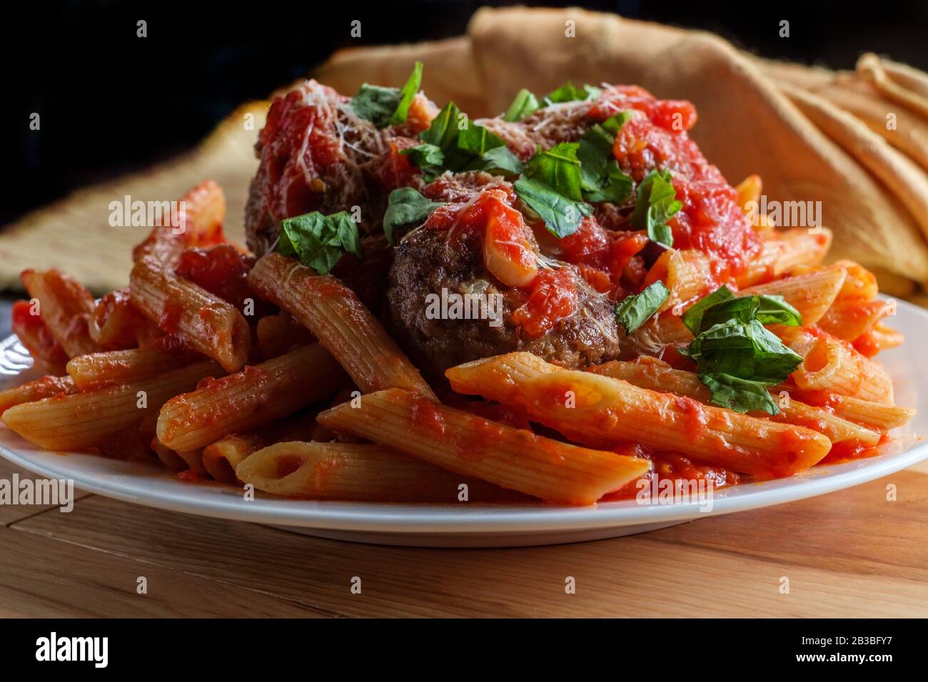 Italian penne rigate pasta with sugo all'arrabbiata sauce and meatballs  garnished with chopped basil and parmesan cheese Stock Photo - Alamy