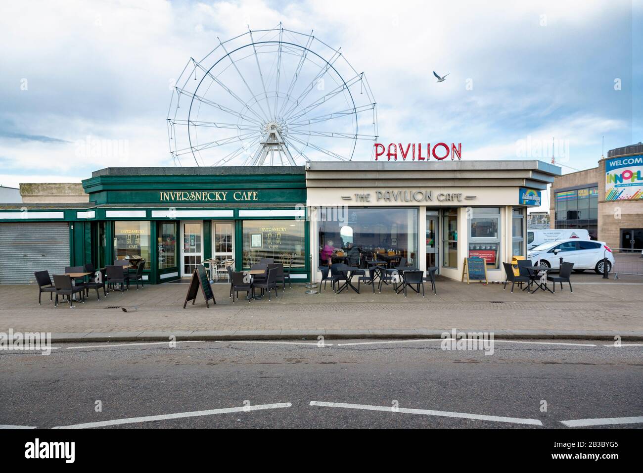 Frontal view of the Pavillion Cafe and the Inversnecky cafe, the Ferris Wheel of Codonas Amusement Park in the background, Seagull flying, Aberdeen Stock Photo
