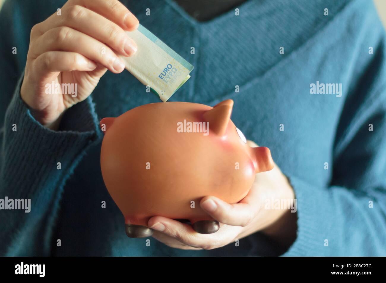 woman holds piggy bank in one hand and a banknote in the other Stock ...