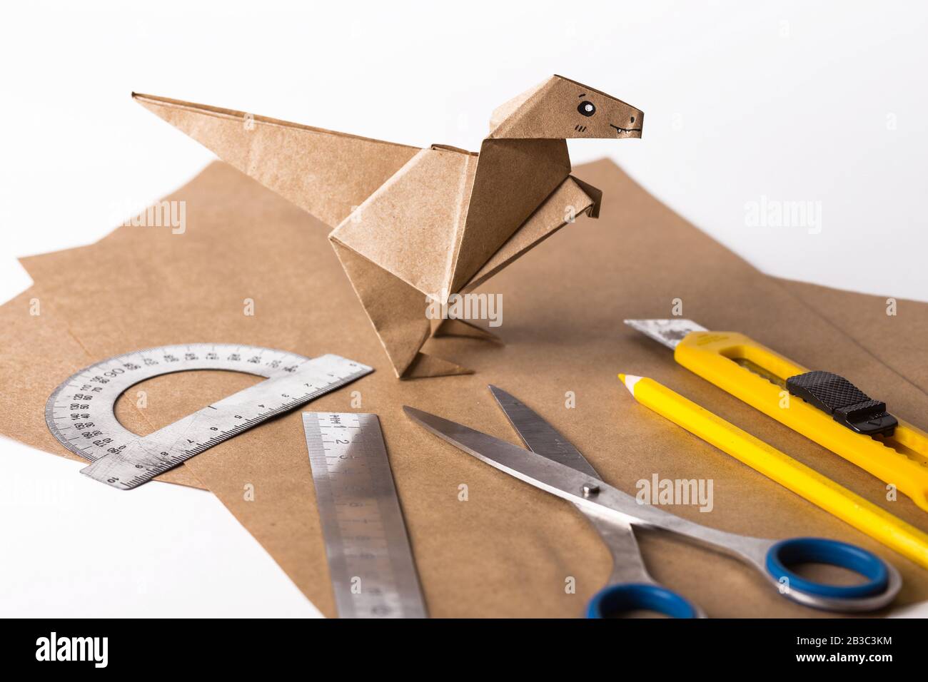 origami dinosaur made of paper. paper, ruler, pencils, knife. interesting hobby Stock Photo