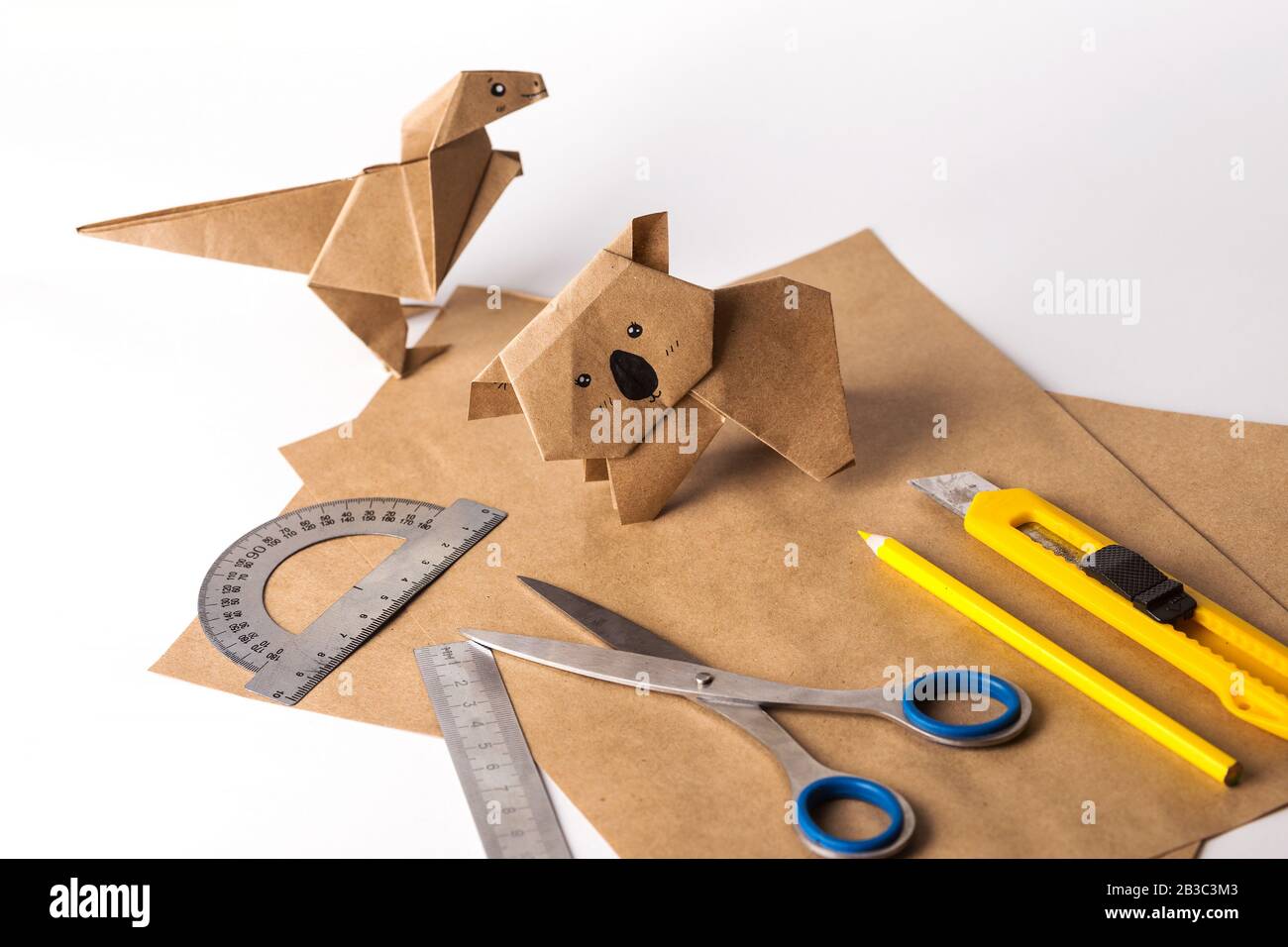 origami dinosaur and koala made of paper. paper, ruler, pencils, knife. interesting hobby Stock Photo
