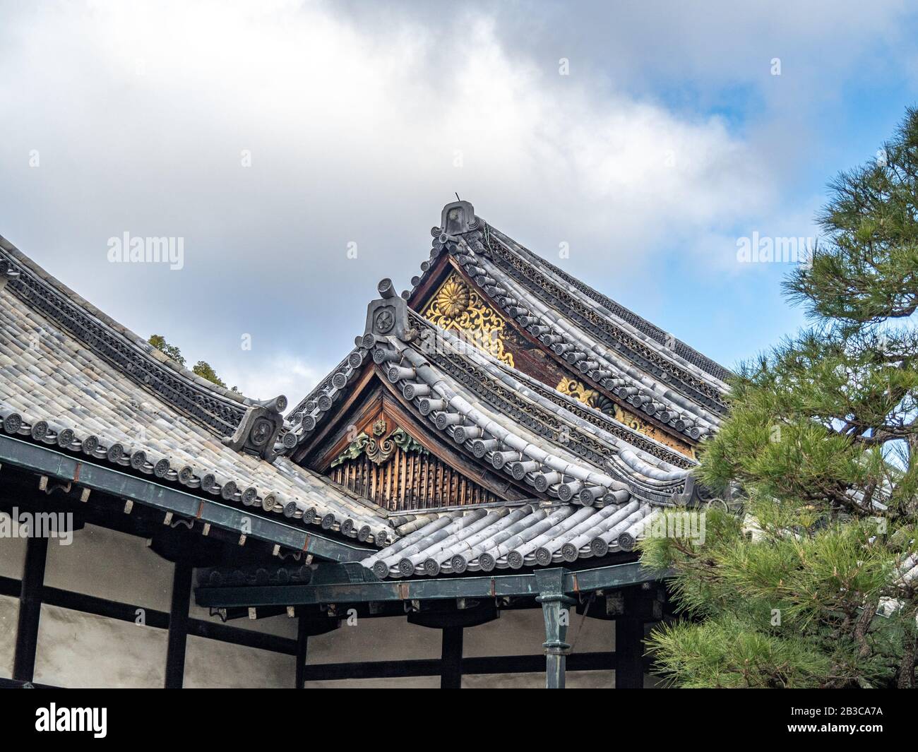 : Traditional Japanese peaked roofs with Imperial Chrysanthemum symbols, blue sky, white clouds, and copy space. Stock Photo