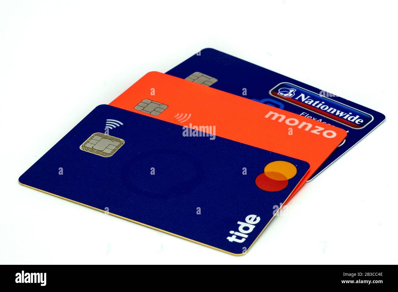 three debit cards stacked on a white background Monzo bank, Tide bank and Nationwide building society Stock Photo