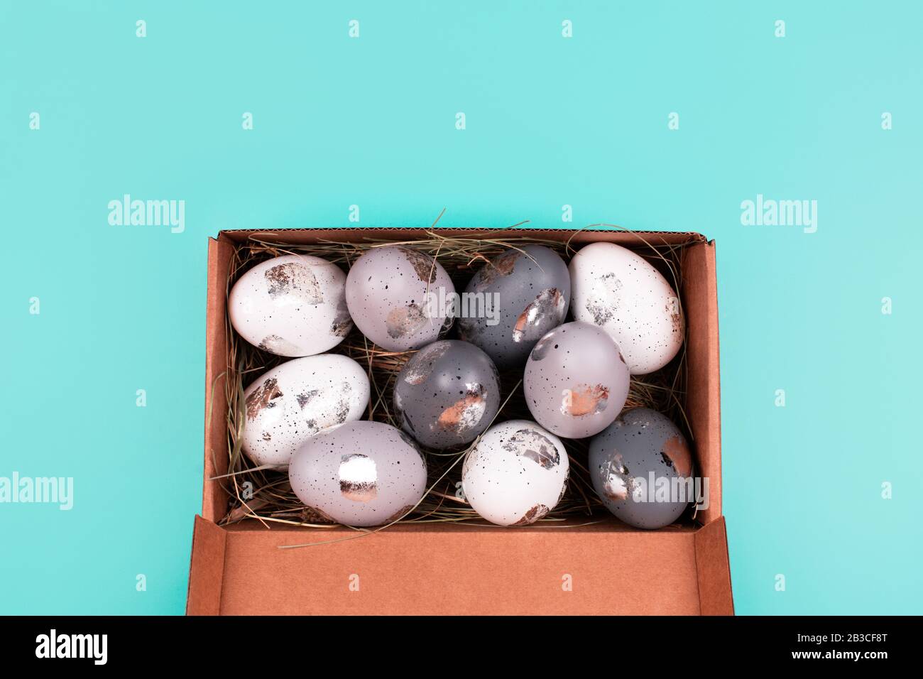 Silver painted decorative eggs in wooden box on pastel blue background. Easter concept. Place for text. Stock Photo