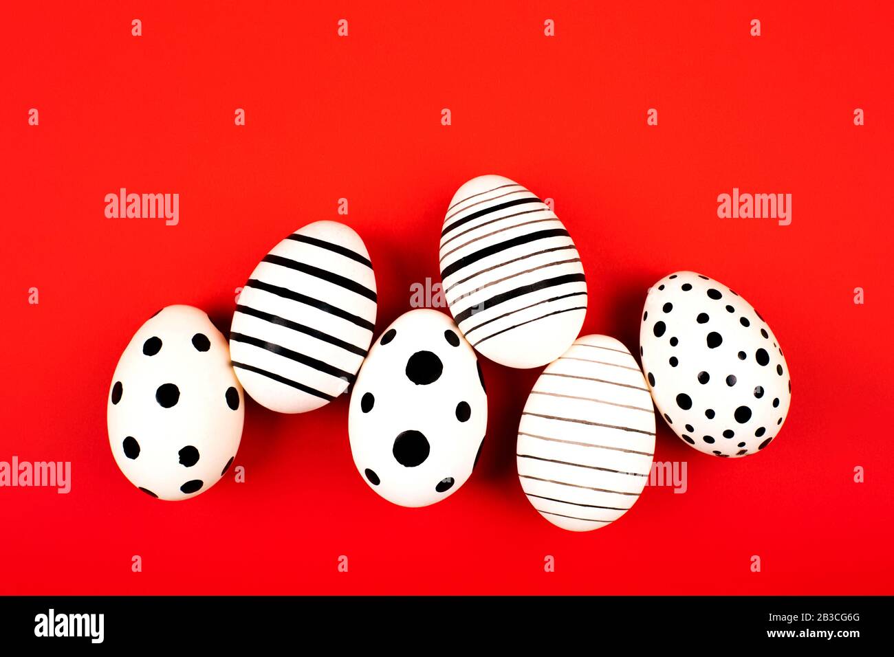 Different graphic hand-painted eggs on bright red background. Easter concept. Flat lay style. Stock Photo