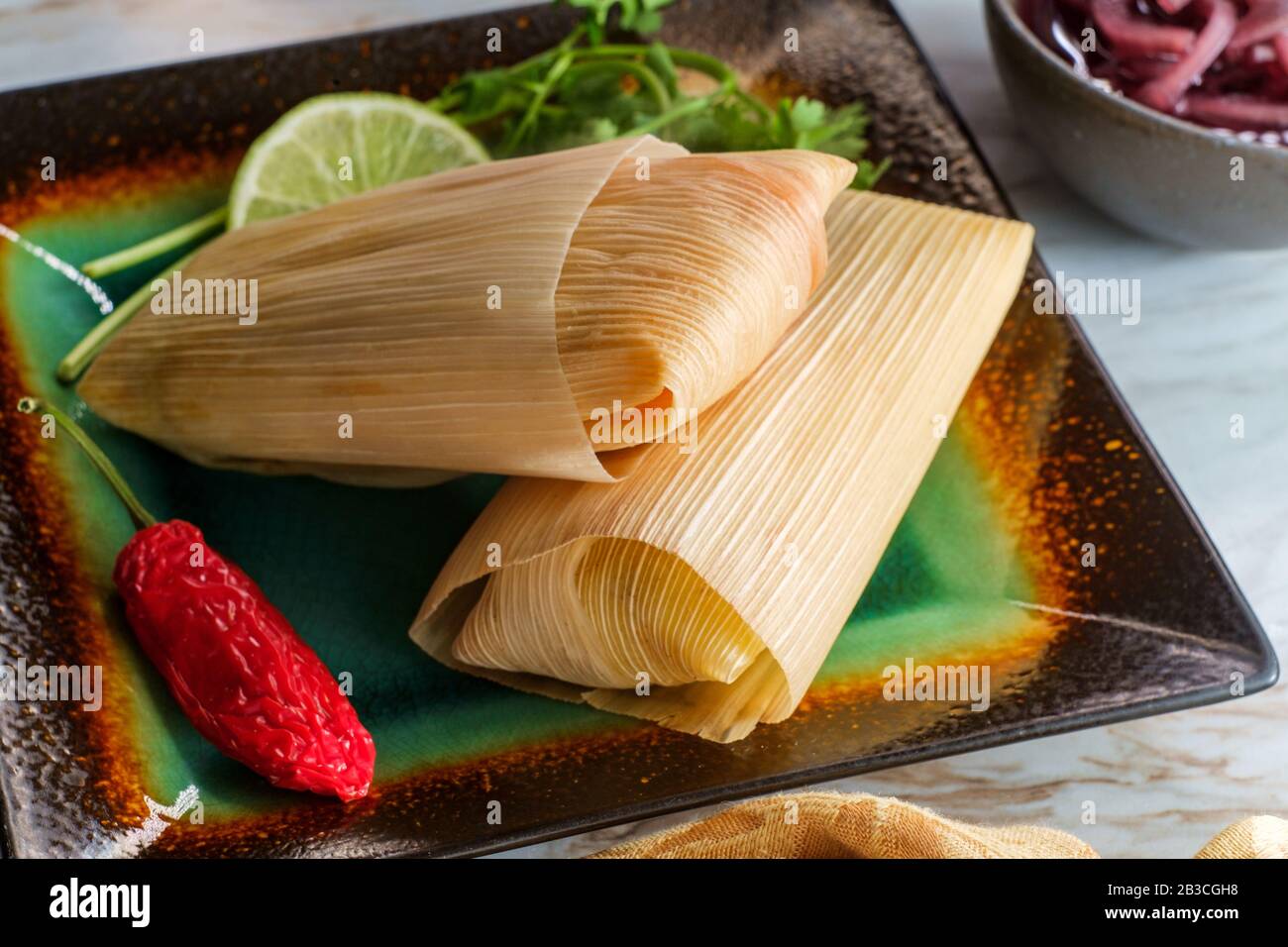 Mexican steamed chili and cheese masa tamales wrapped in corn husk Stock Photo
