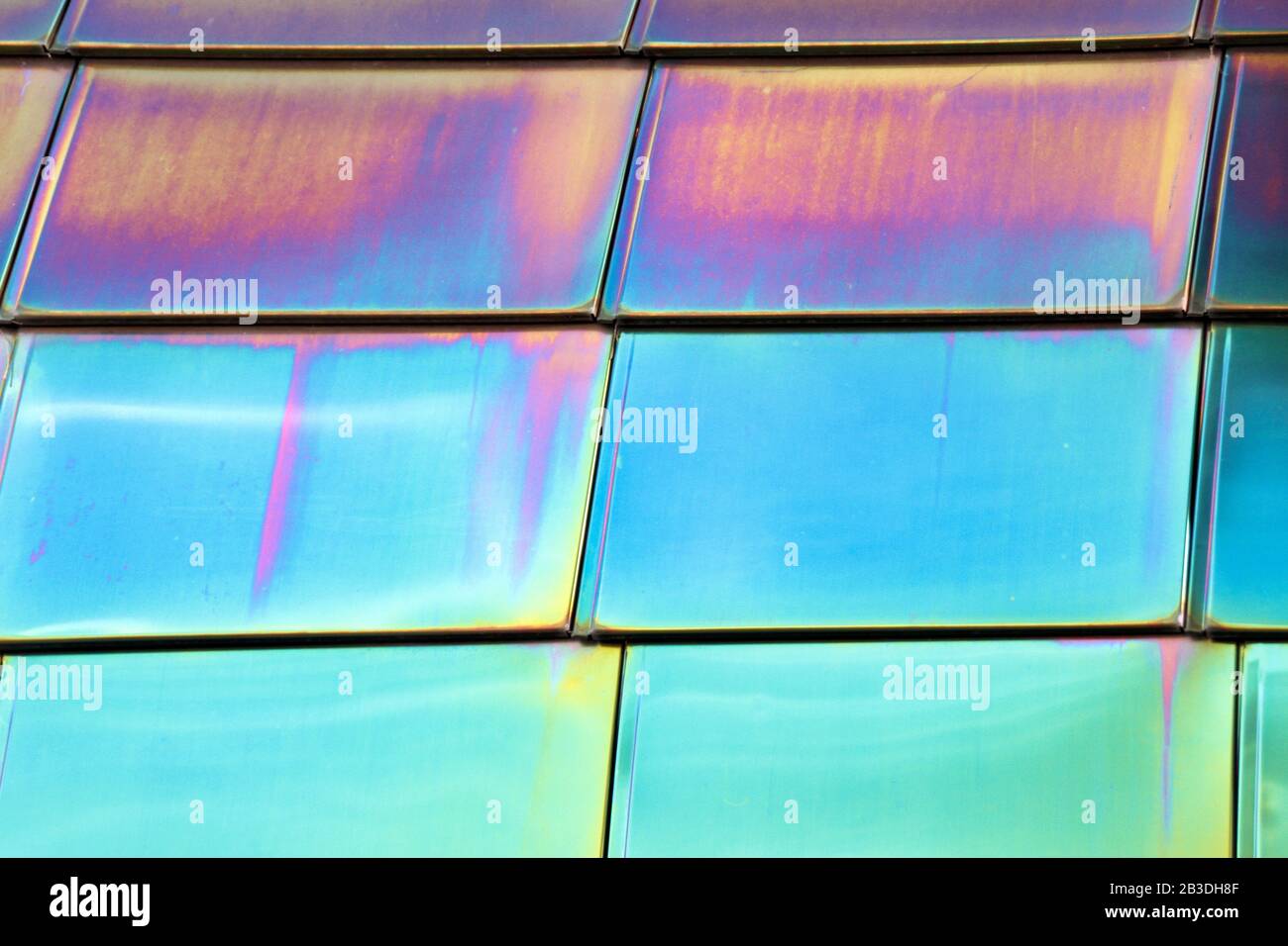 Reflective mirrored metal tiles show neon blue and pink. Stock Photo