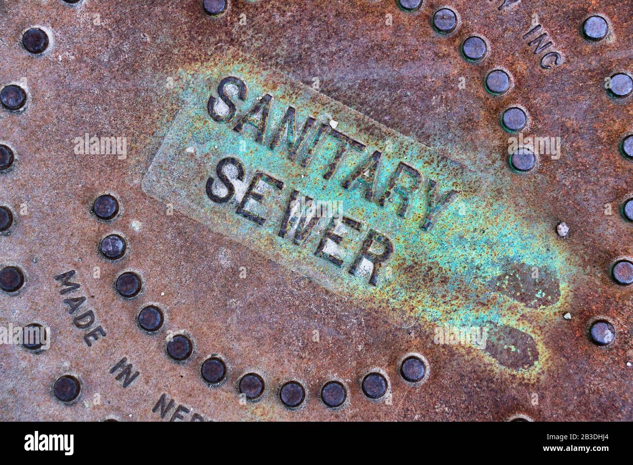 A close up view of a the brown-red and green rusted cover of a sanitation department. Stock Photo