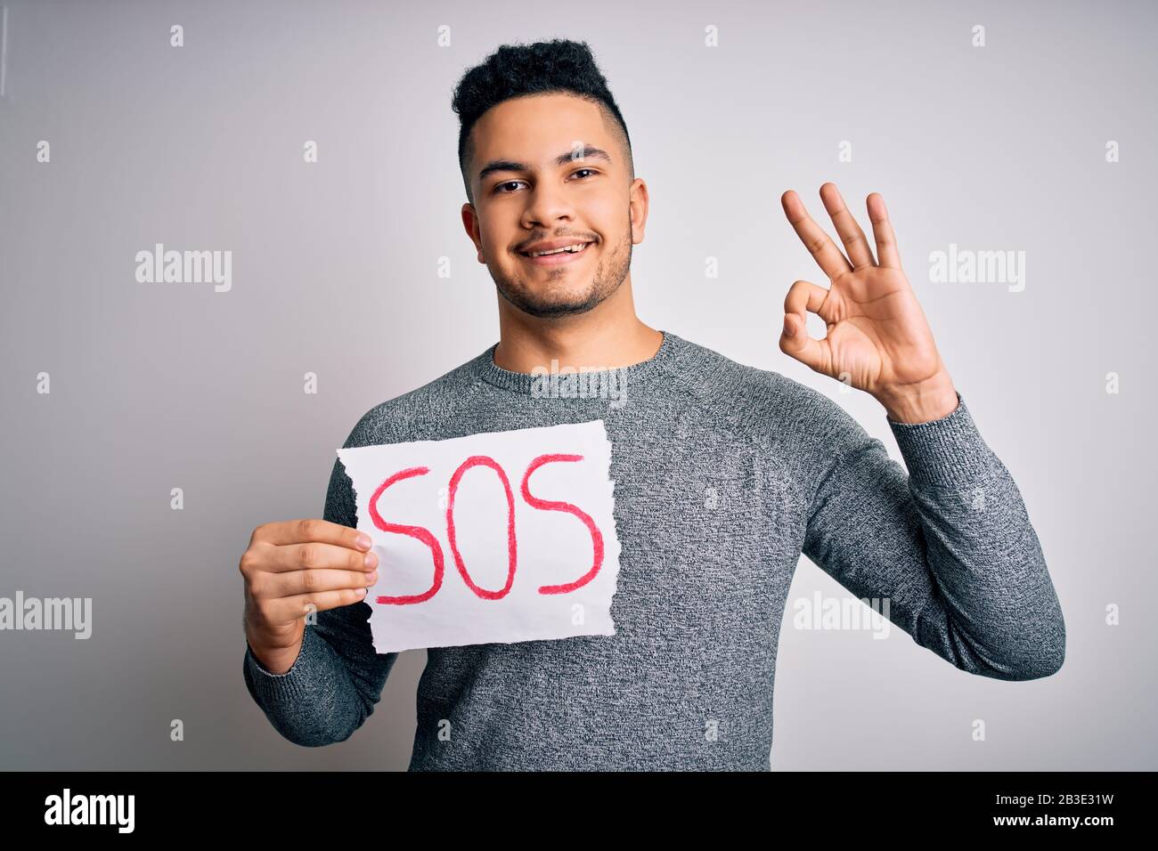 Young handsome man with problem holding banner with sos message over ...