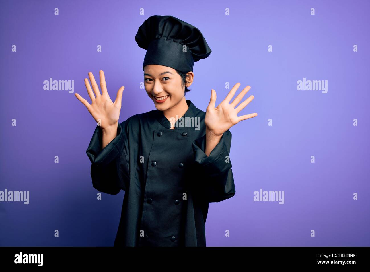 Young beautiful chinese chef woman wearing cooker uniform and hat over