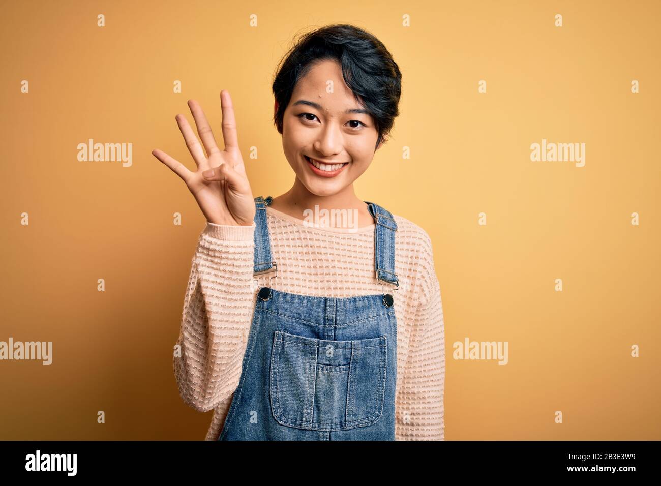 Young beautiful asian girl wearing casual denim overalls over isolated ...