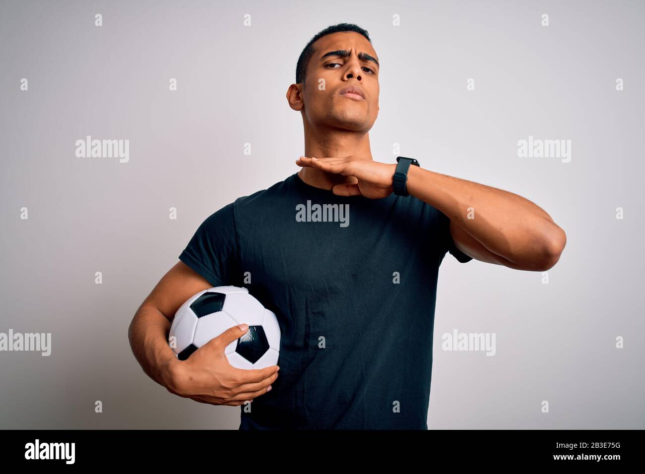 Handsome african american man playing footbal holding soccer ball over