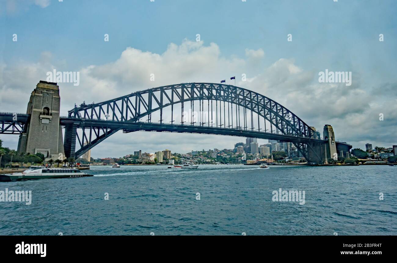 Sydney Harbour Bridge viewed from the water with four groups of tourists walking over the arch. Stock Photo