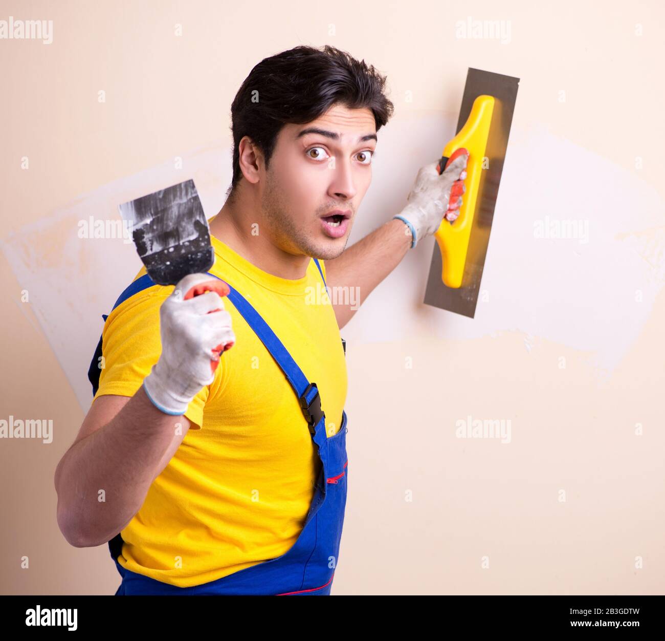 The young contractor employee applying plaster on wall Stock Photo