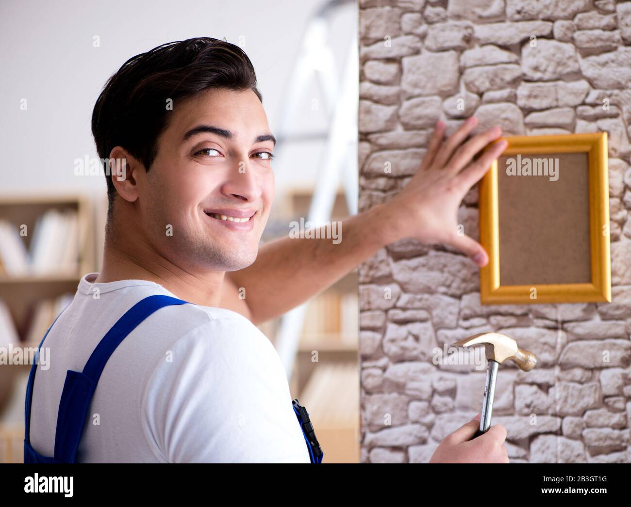 The repairman putting picture frame onto wall Stock Photo Alamy