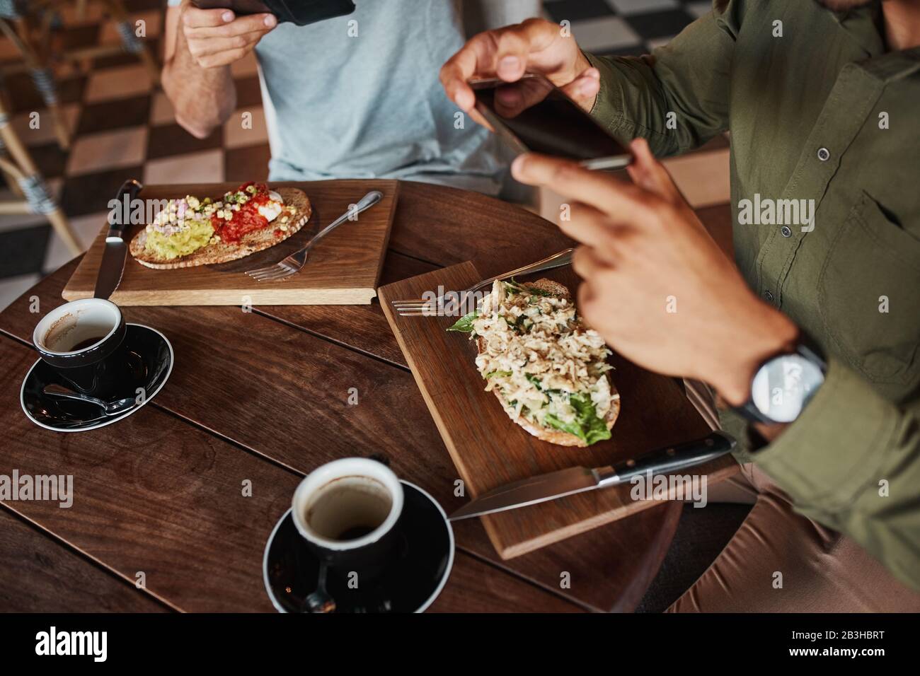 Closeup of man hand clicking photo of italian bruschetta with coffee in cafe while enjoying lunch Stock Photo