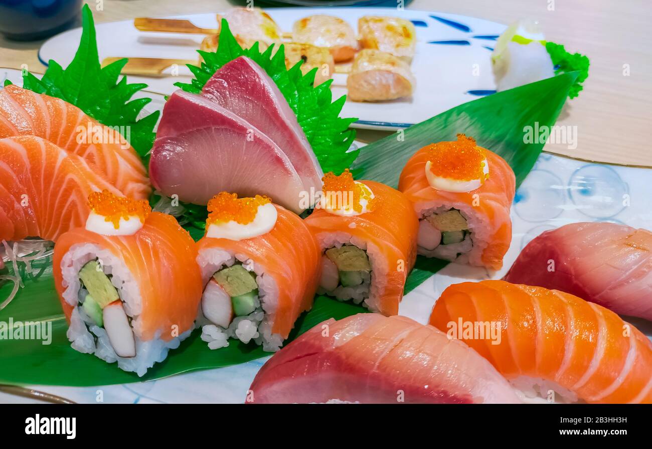 Japanese food combo set on white plate. Salmon sushi, sashimi, and nigiri on restaurant table. Fish meat sliced and Japan vinegared rice rolls with Stock Photo
