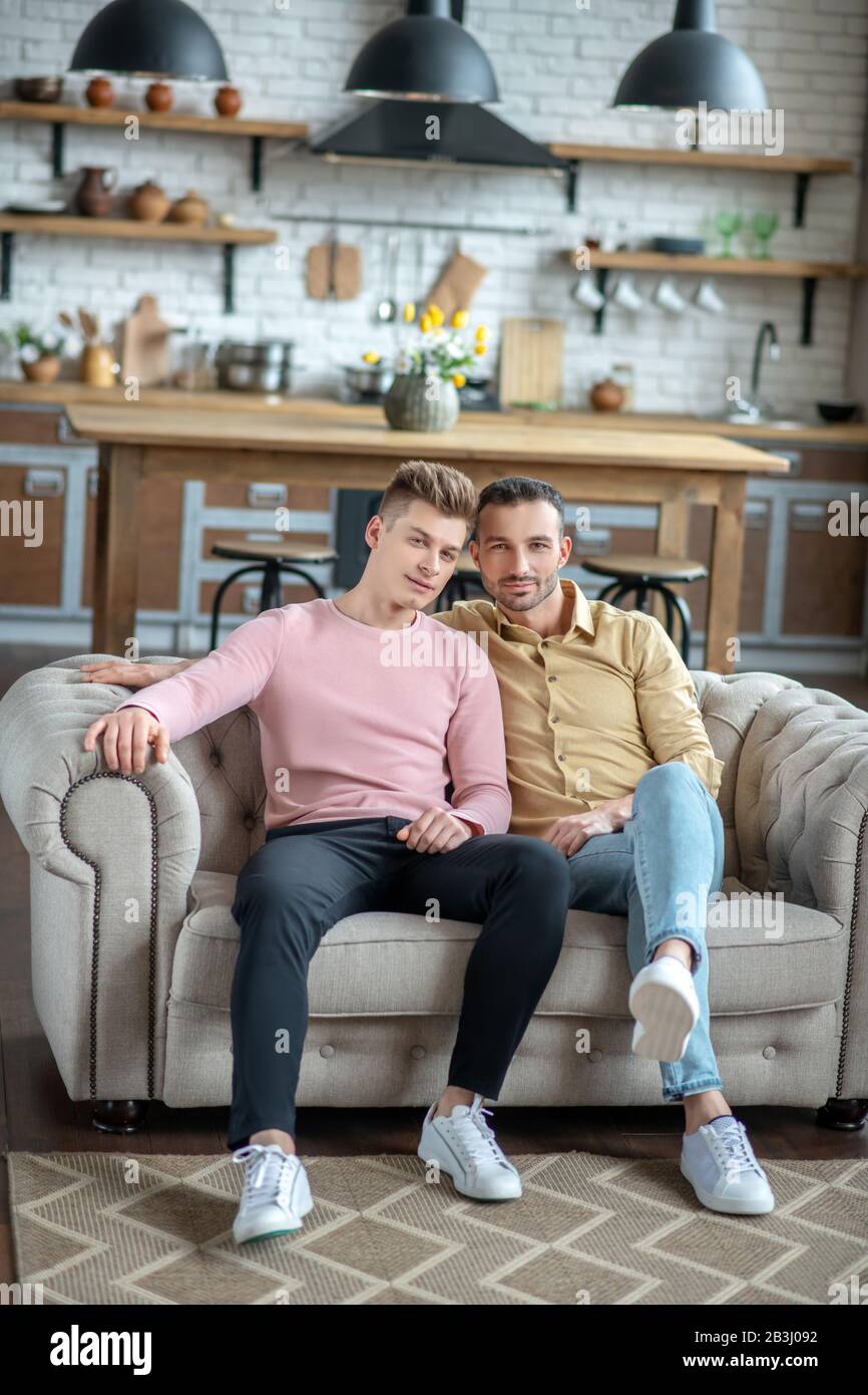 Two young men sitting on the sofa feeling relaxed Stock Photo - Alamy