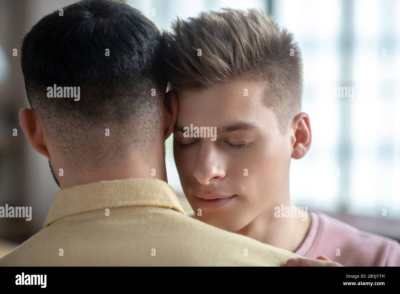 Two men standing next to each other hugging Stock Photo