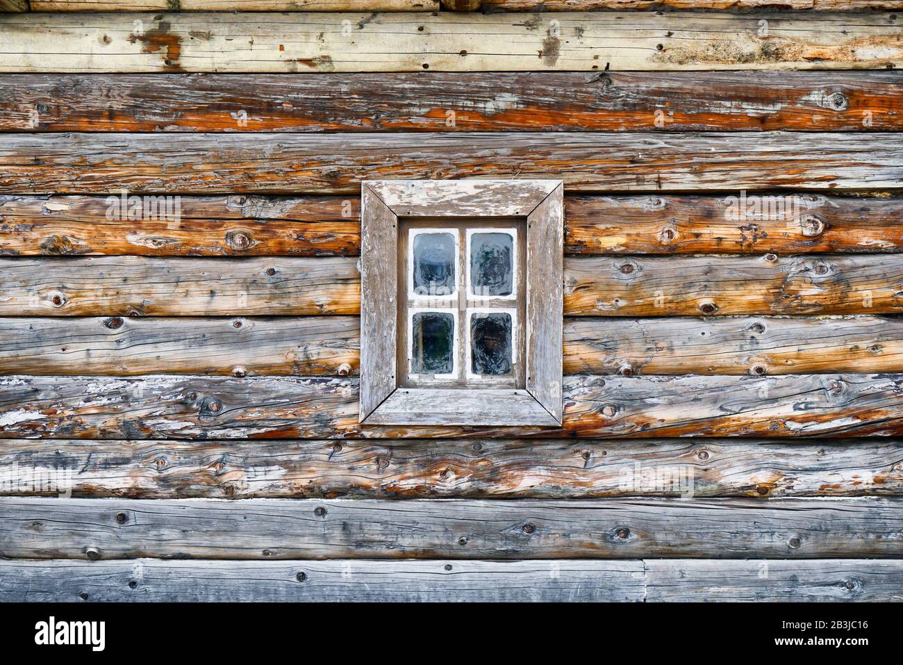 Facade of an old log house with a small window Stock Photo
