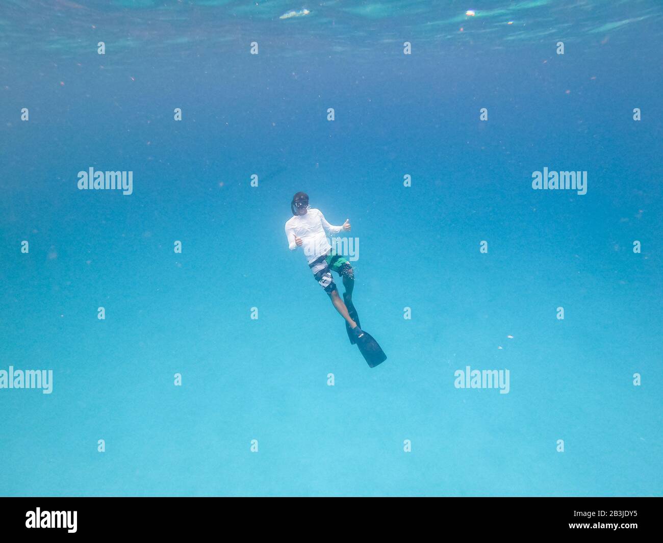 Underwater view of man free diving in blue ocean. Stock Photo