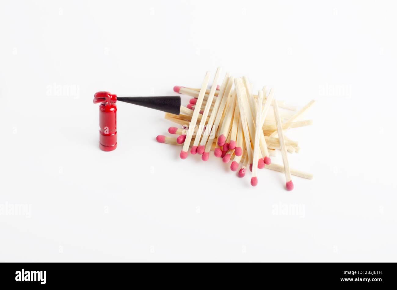 Tiny fire extinguisher close to a pile of unused matches, top-side view Stock Photo
