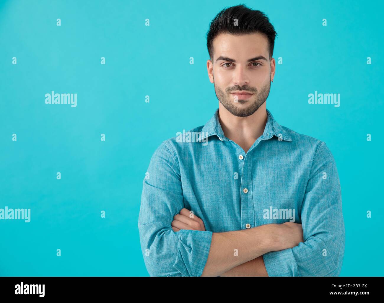 wonderful casual man in blue shirt is standing with his arms crossed
