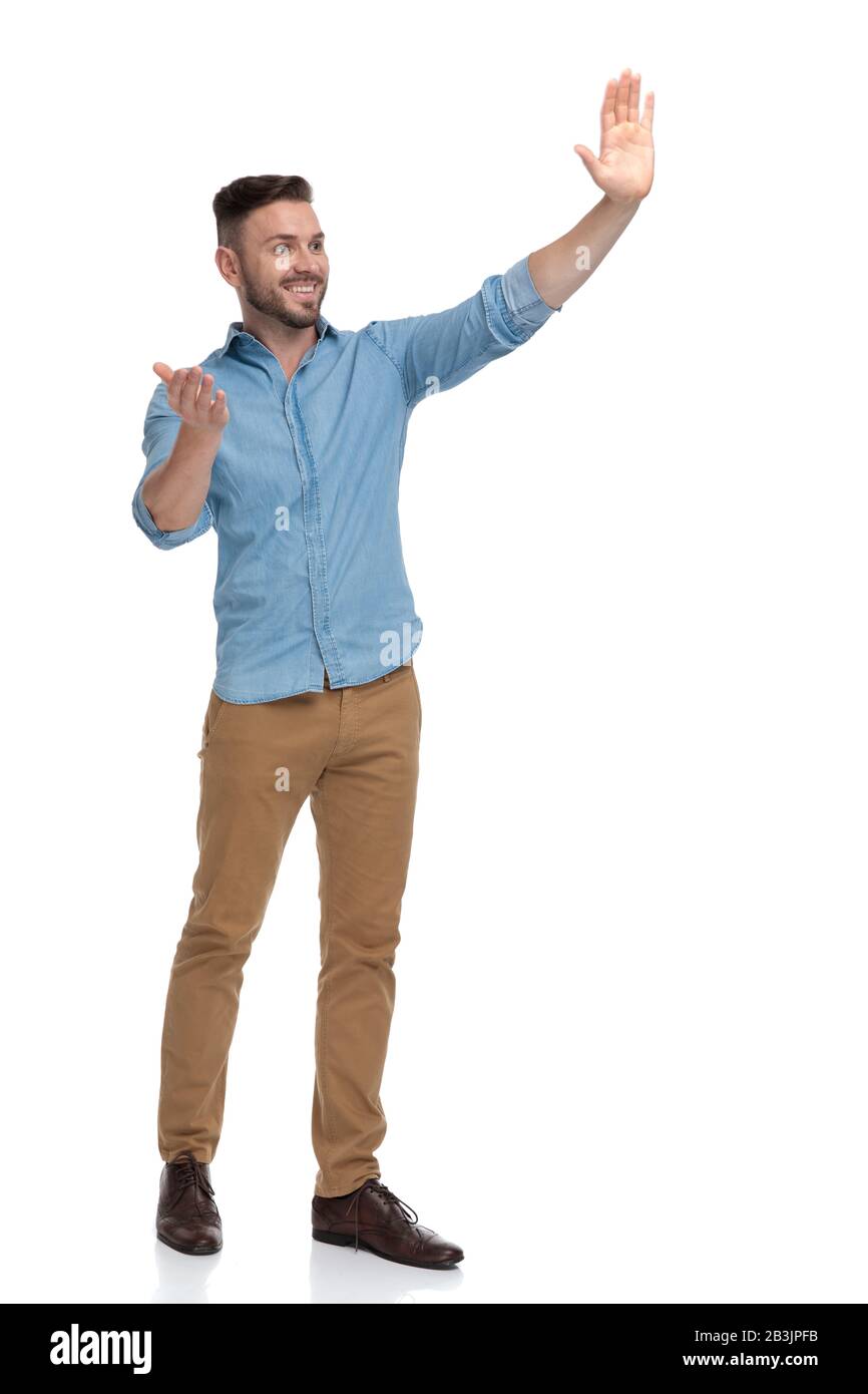 side view of a charming casual man with blue shirt standing and saluting  with a how are you sign gesture happy on white studio background Stock  Photo - Alamy
