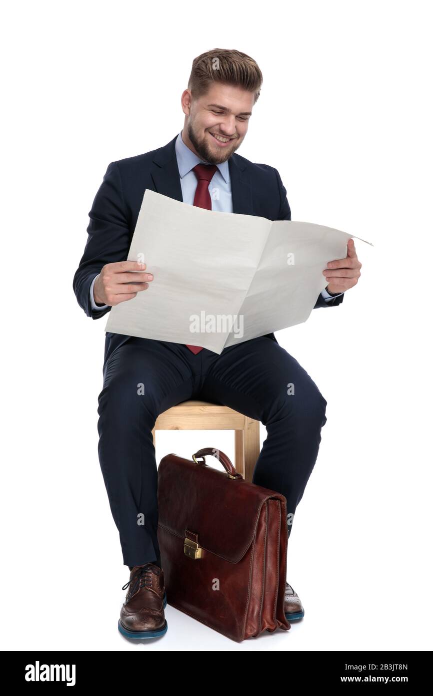 excited young businessman smiling and reading newspaper sitting ...