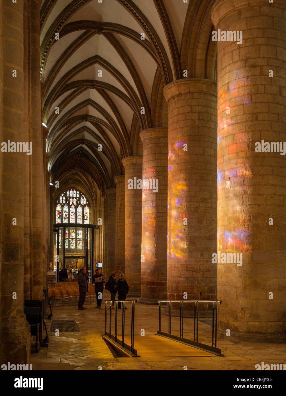Sunlight floods through stained glass windows onto the main piers in Gloucester Cathedral. Stock Photo