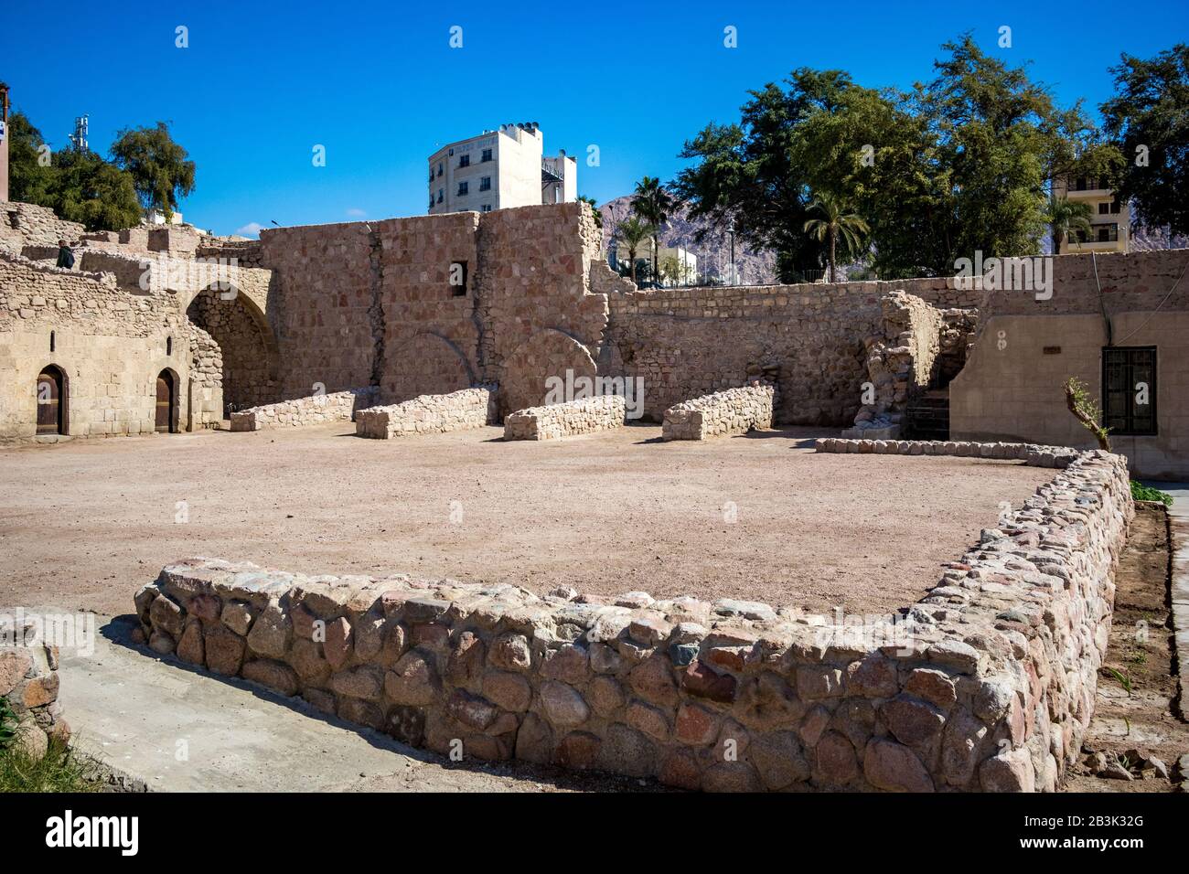 AQABA, JORDAN - JANUARY 31, 2020: Tourists walk on fortress walls. Court yard view of Aqaba Castle. The main fort square is empty under the sunlight. Sunny winter day. Clear cloudless blue sky Stock Photo