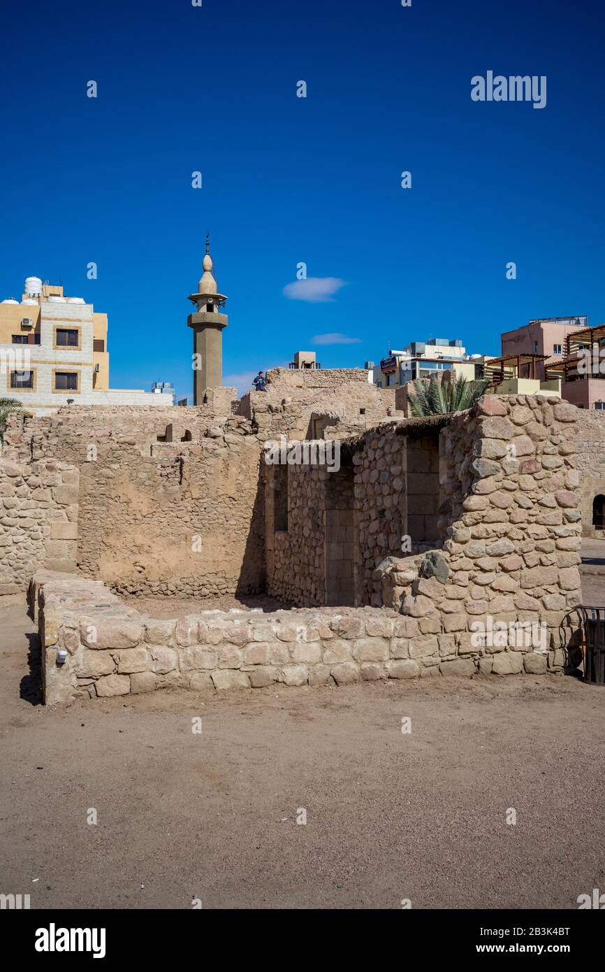 AQABA, JORDAN - JANUARY 31, 2020: Tourists walk on fortress walls. Court yard view of Aqaba Castle. The main fort square is empty under the sunlight. Sunny winter day. Clear cloudless blue sky Stock Photo
