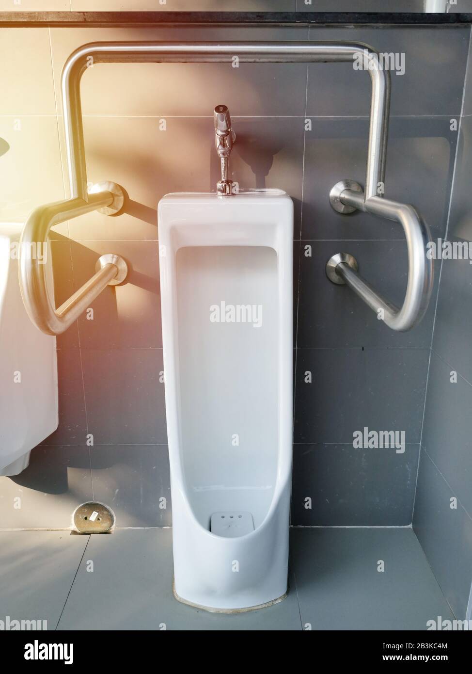 urinal with handrails for disabled person in public restroom Stock