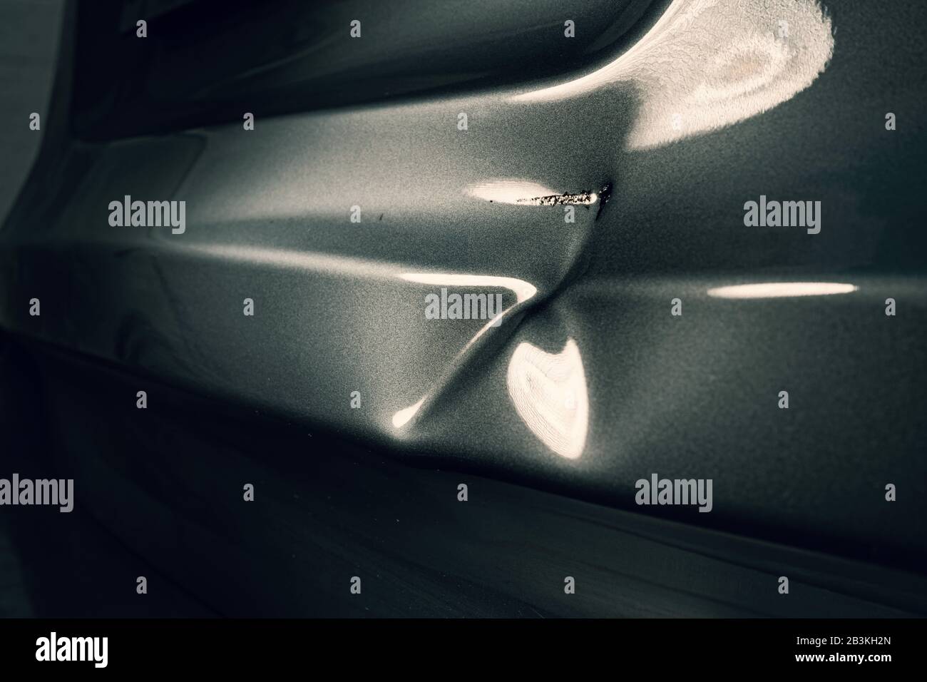 A dent in the body of a silver car in exciting light. Stock Photo