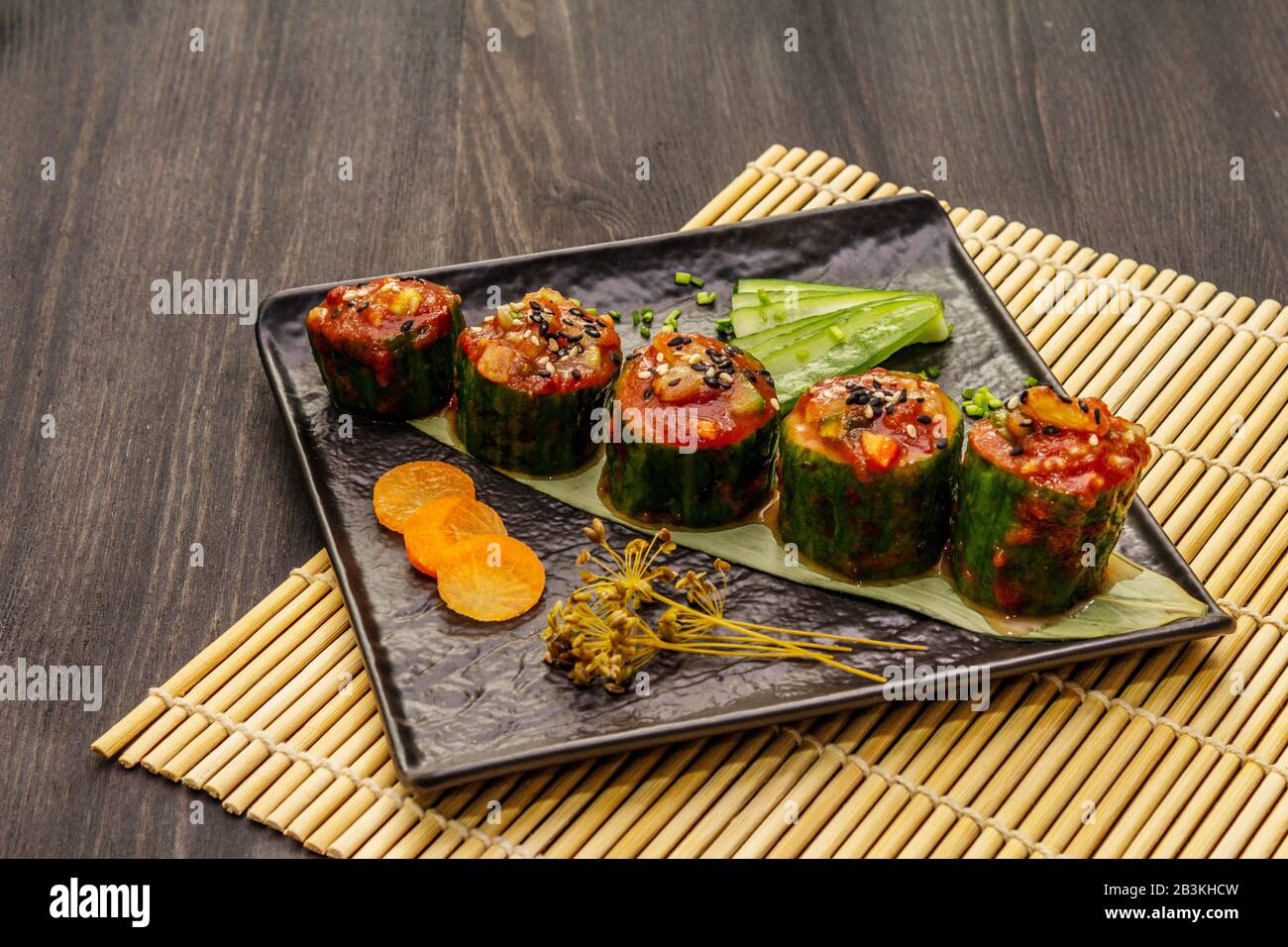 Korean style stuffed cucumbers. Kojori kimchi spicy snack. Fermented and marinated vegetables. Black wooden boards background, close up Stock Photo