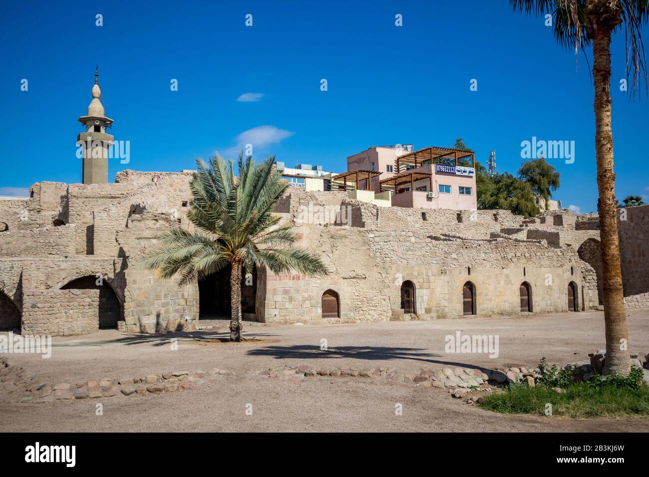 AQABA, JORDAN - JANUARY 31, 2020: Tourists can walk on fortress walls. Court yard view of Aqaba Castle. The main fort square is empty under the sunlight. Sunny winter day. Clear cloudless blue sky Stock Photo