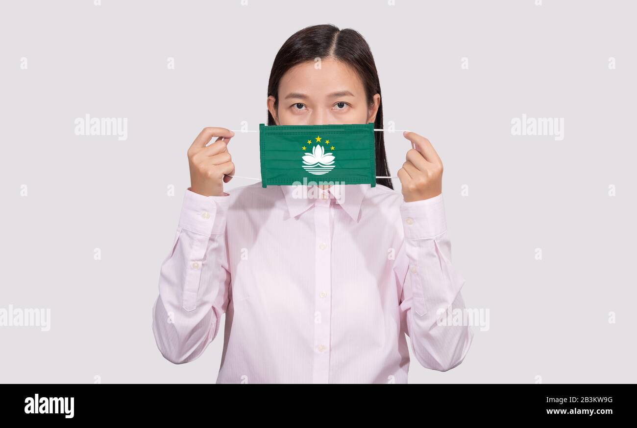 Asian woman wearing hygienic face mask painting Macau flag to protect from the Coronavirus 2019 (COVID-19) infection outbreak situation, the virus ori Stock Photo