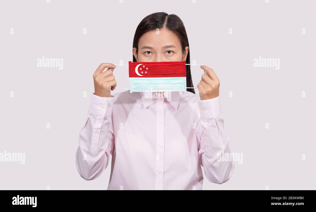 Asian woman wearing hygienic face mask painting Singapore flag to