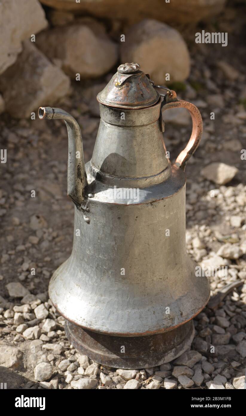 The old brass teapot is situated against stones background. This teapot