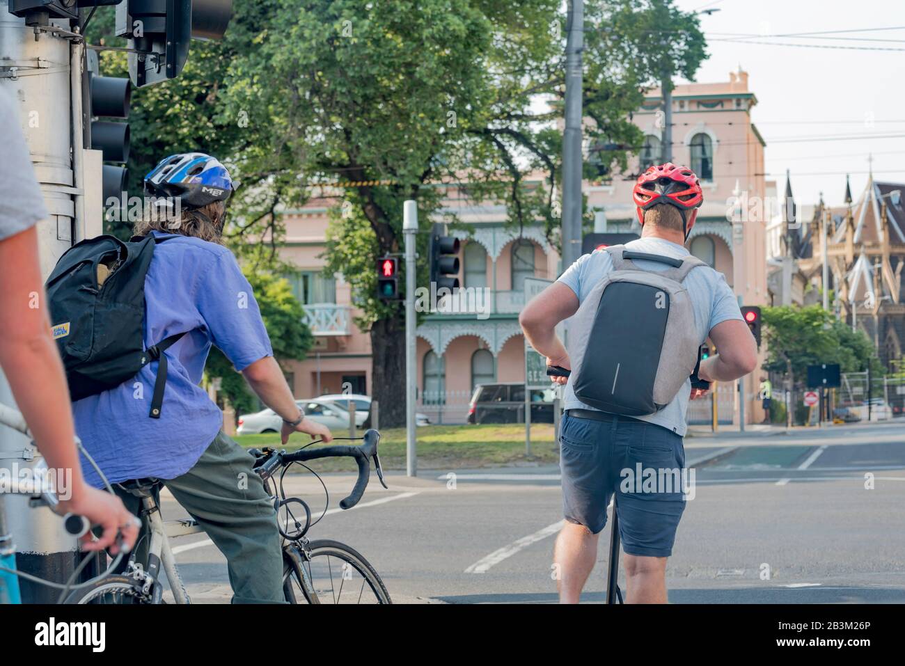 Cyclists and a scooter rider wait at a set of traffic lights for a green signal on Brunswick Street, Fitzroy as they commute towards the city. Stock Photo
