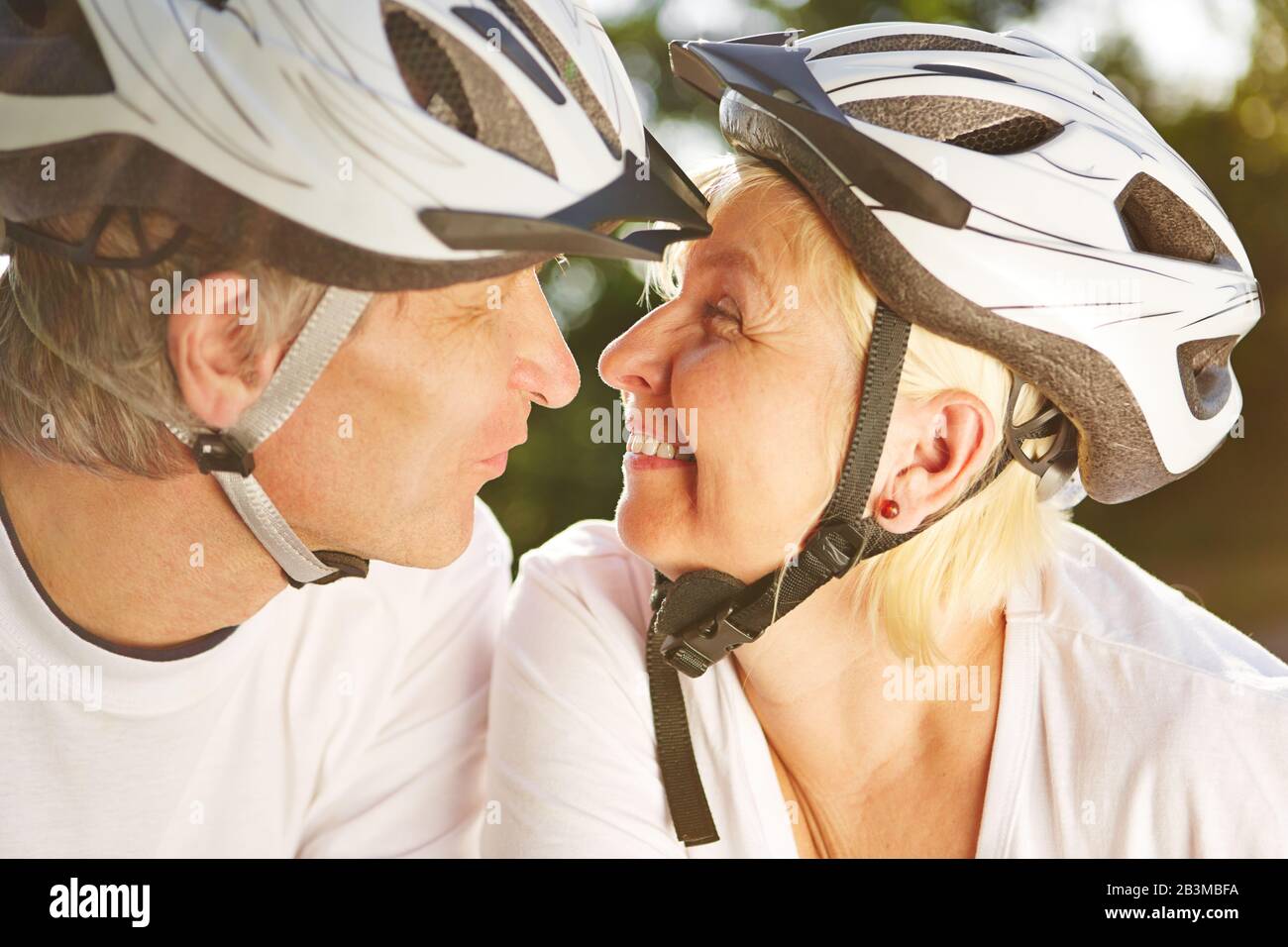 Woman and man with bicycle helmet kiss on a bike tour Stock Photo