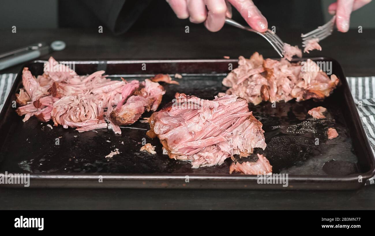 Step by step. Shredding pork roast shoulder with two forks Stock Photo