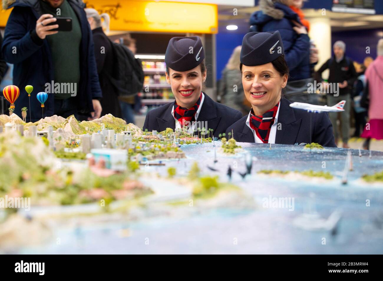 British Airways cabin crew Olivia Welch (left) and Julie Diggins with a 20-by-20-foot model of California at Visit California's 'Minifornia: An Epic Road Trip Experience' at Waterloo Station, London. PA Photo. Picture date: Thursday March 5, 2020. The Minifornia experience, which is open until March 7, includes a convoy of miniature cars and RVs 'road-tripping' on four routes across the custom built model. Designed and built by Hollywood set builders, Minifornia captures footage of road-trip journeys transmitted live to users wearing video headsets and across large screens in Stock Photo