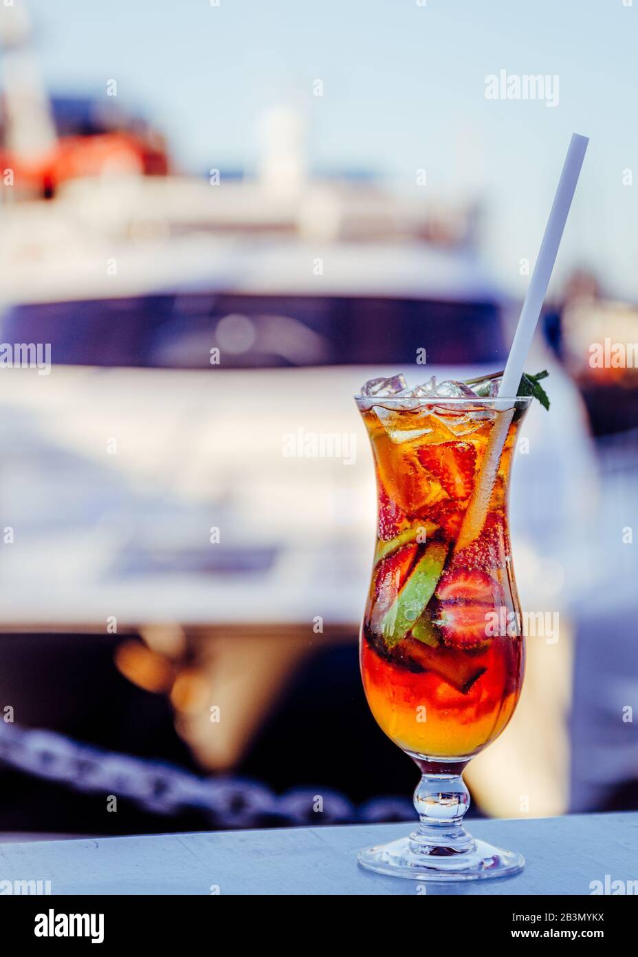 Close up of refreshing cocktail drink with juicy red looking lips inside glass with boat in background.Cape Town SA Stock Photo
