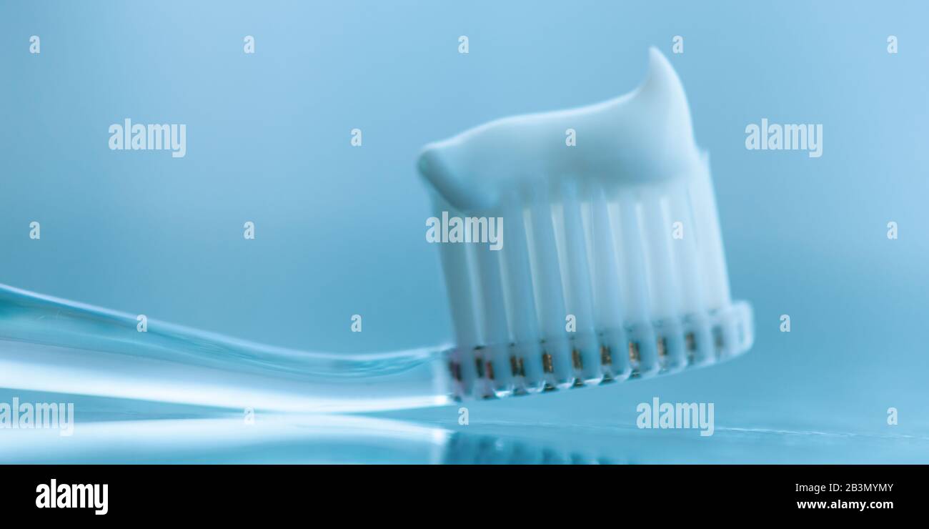 Transparent plastic toothbrush with white toothpaste. Macro image. Stock Photo