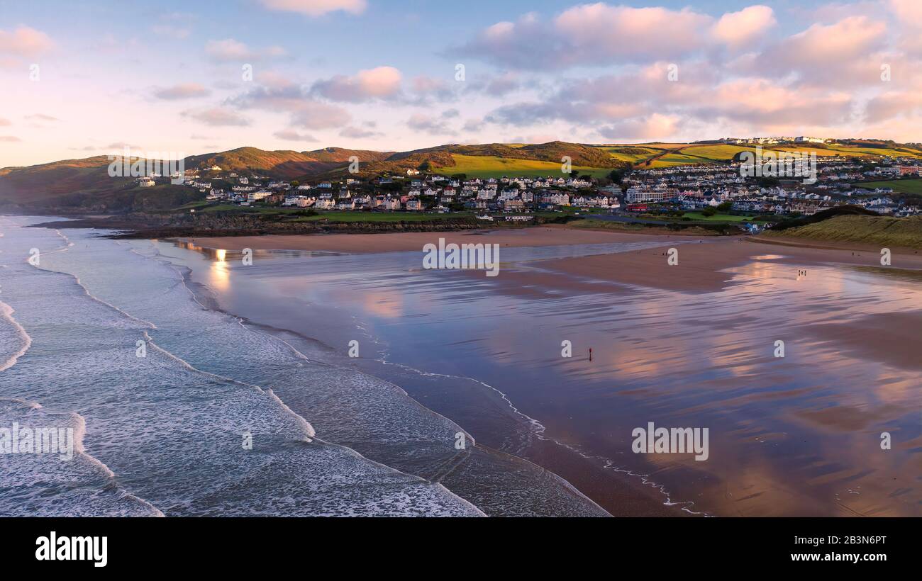 Aerial view of the town of Woolacombe and it's beach at dawn, waves breaking on a beach, the clouds reflected in the wet sand Stock Photo